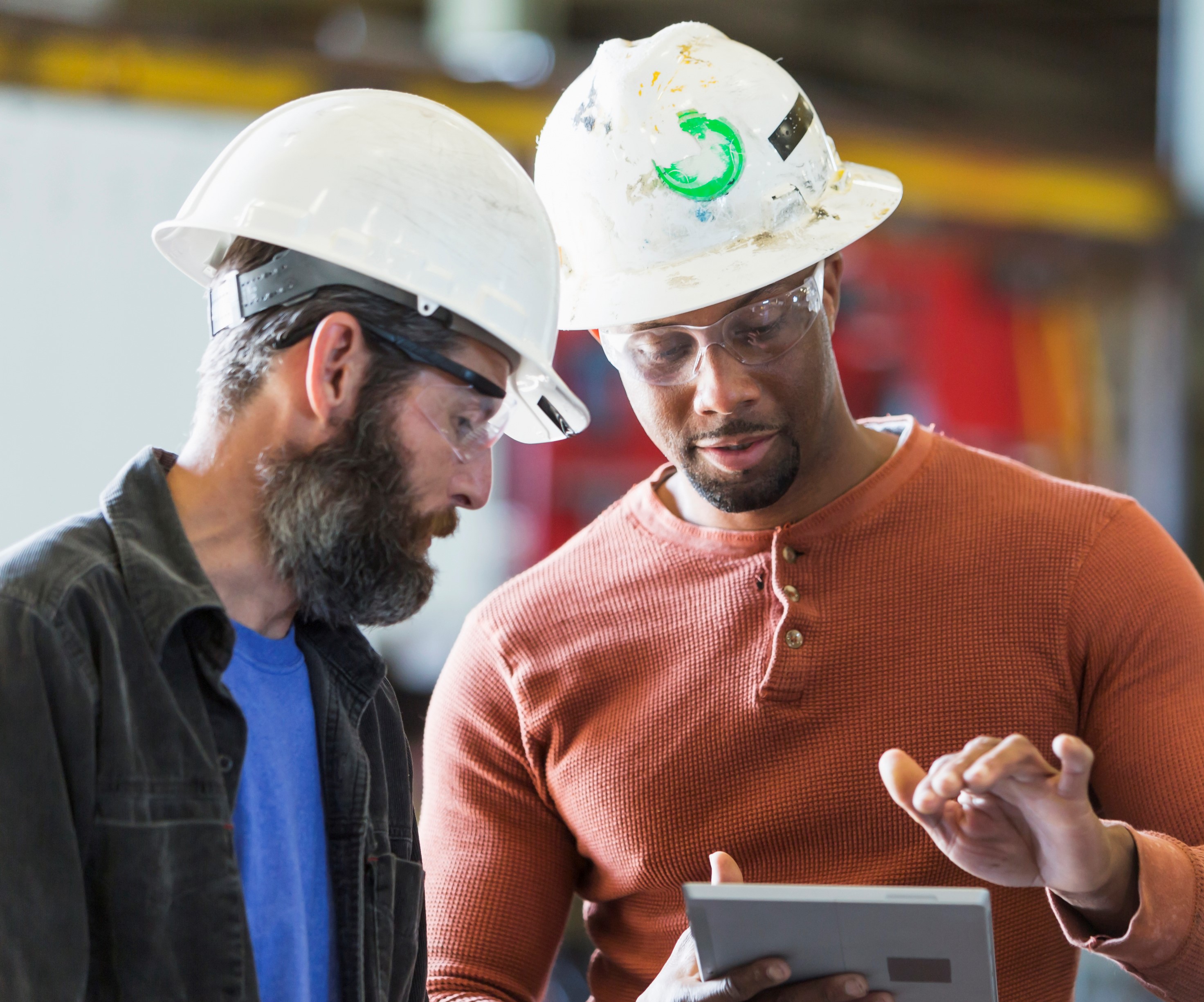 Two workers wearing hardhats using digital tablet Manufactured In
